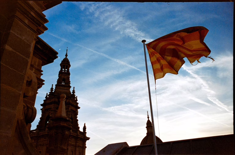 Catalan flag waving with historical architecture against a vibrant sky in Barcelona.