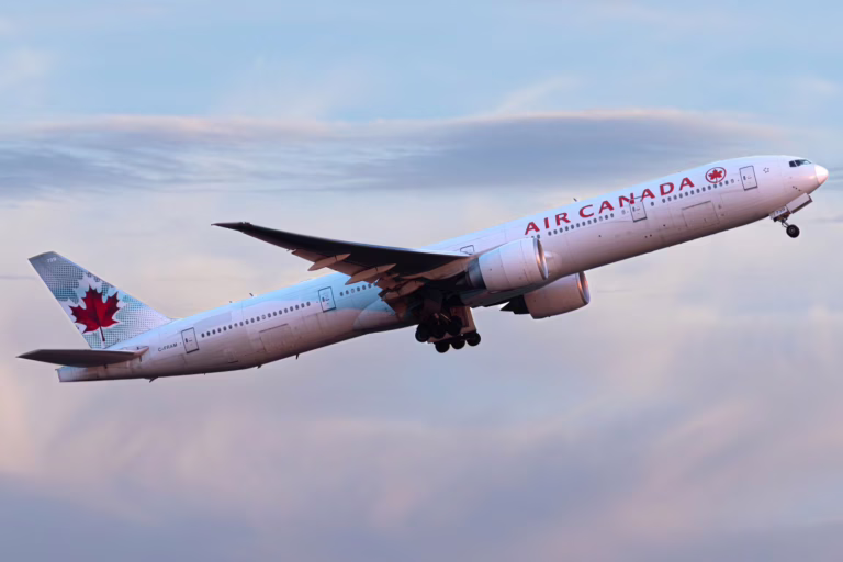 Air Canada aircraft ascending during sunset against a pink sky.