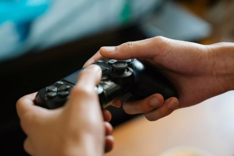 Crop unrecognizable man with modern gamepad playing video game while having free time at home