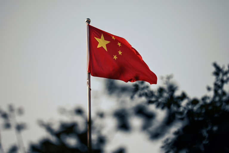 A chinese flag waves against a cloudy sky.